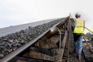 An image of coal being transported on a conveyor belt in a mining environment
