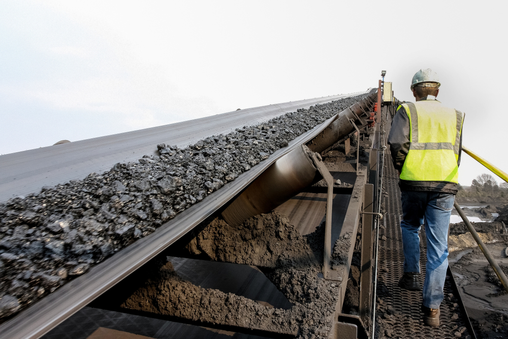An image of coal being transported on a conveyor belt in a mining environment