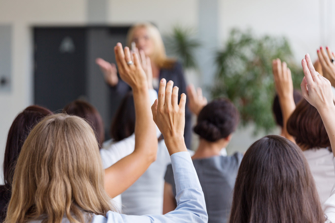 People putting up their hands to bid while participating in an auction